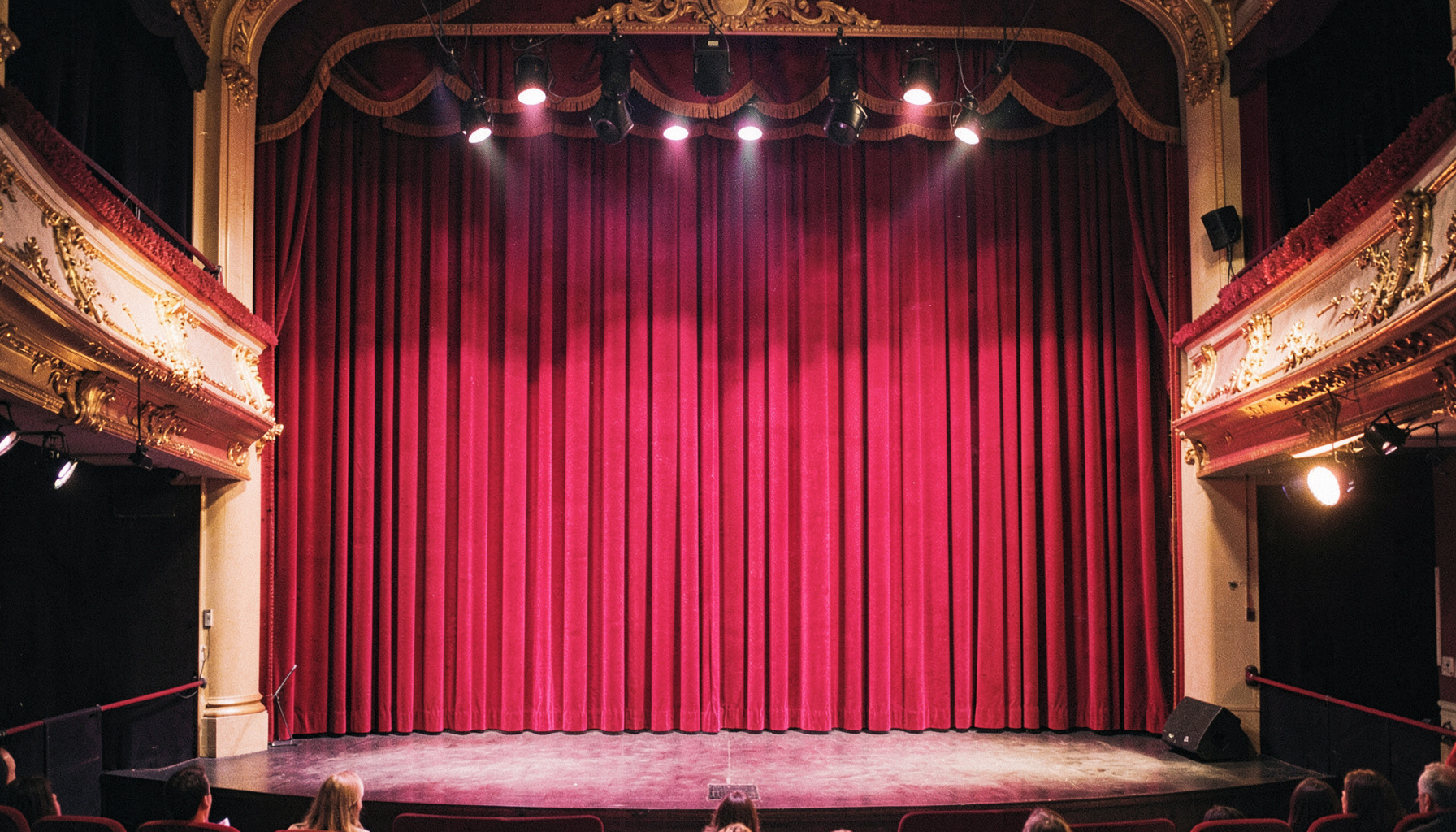 Palco de teatro com cortinas vermelhas e holofotes dourados, ambiente clássico