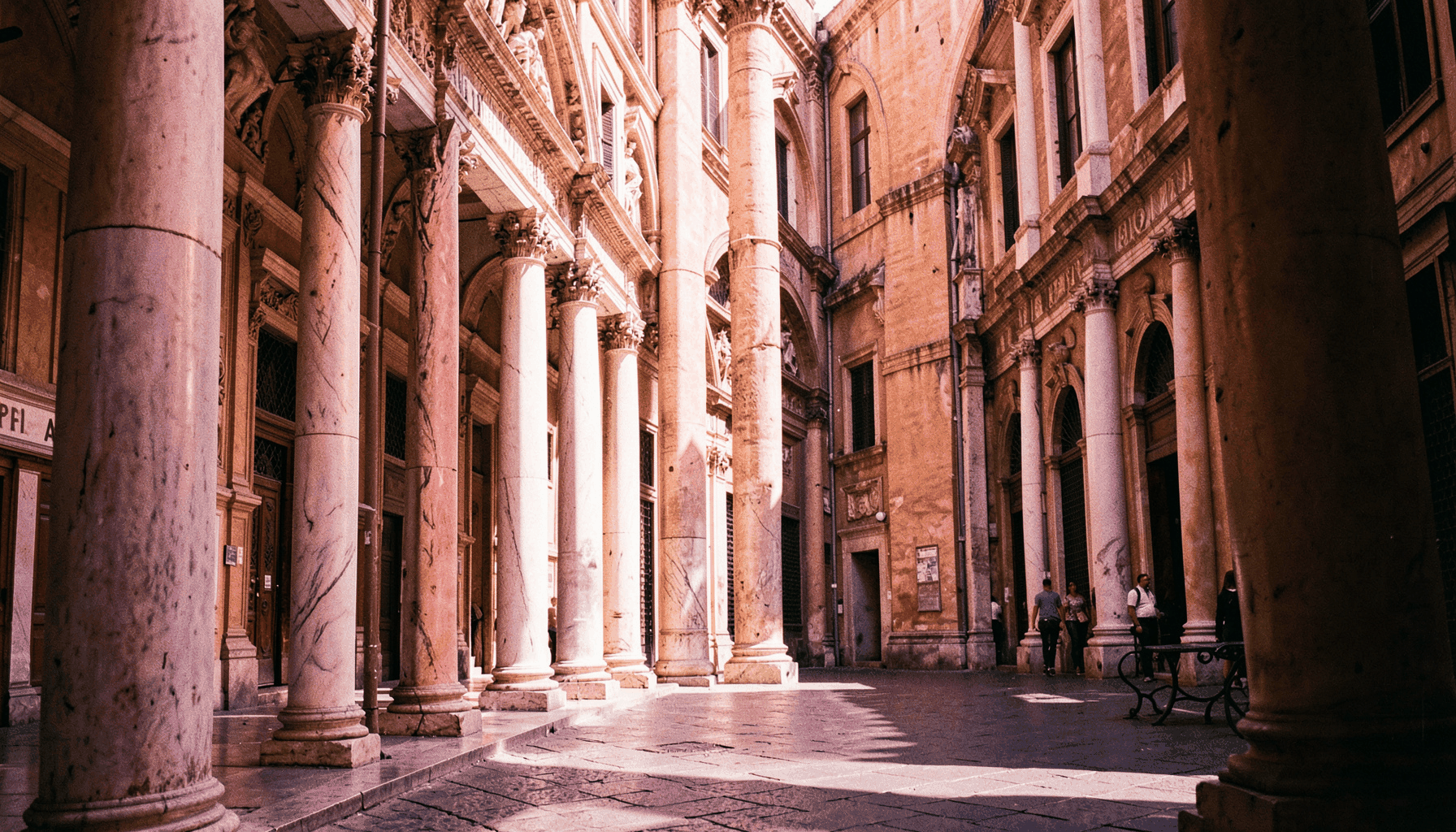 Ruas da Roma antiga com colunas de mármore e luz solar intensa, tons de terracota e dourado
